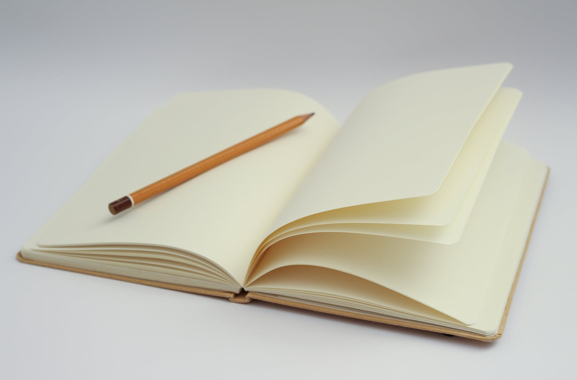 white notebook and yellow pencil